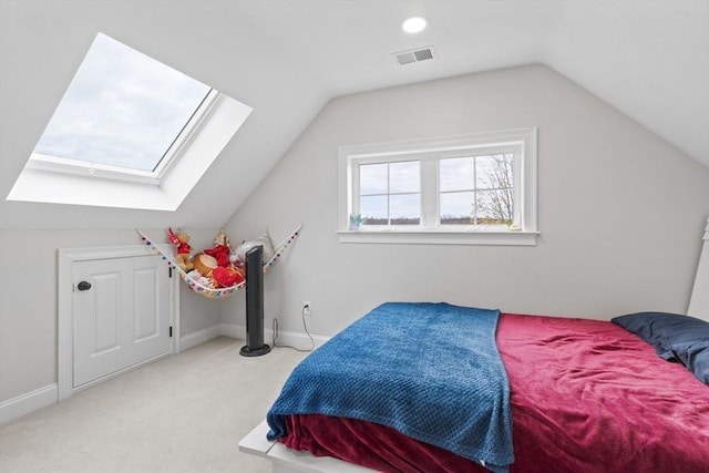 bedroom with vaulted ceiling with skylight, baseboards, light carpet, and visible vents