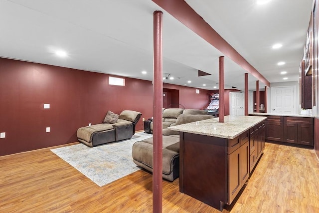 kitchen featuring a center island, recessed lighting, light wood finished floors, and light stone countertops