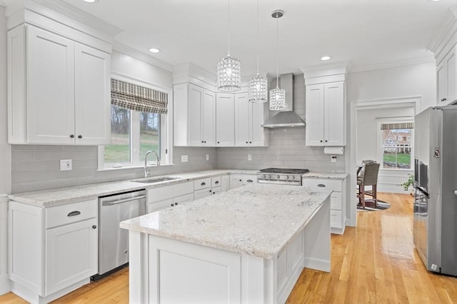kitchen featuring wall chimney range hood, a sink, a notable chandelier, ornamental molding, and stainless steel appliances