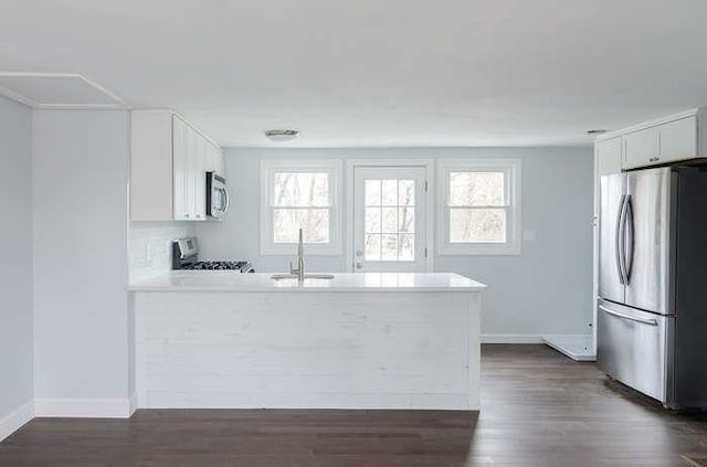 kitchen featuring stainless steel appliances, white cabinetry, a healthy amount of sunlight, and sink