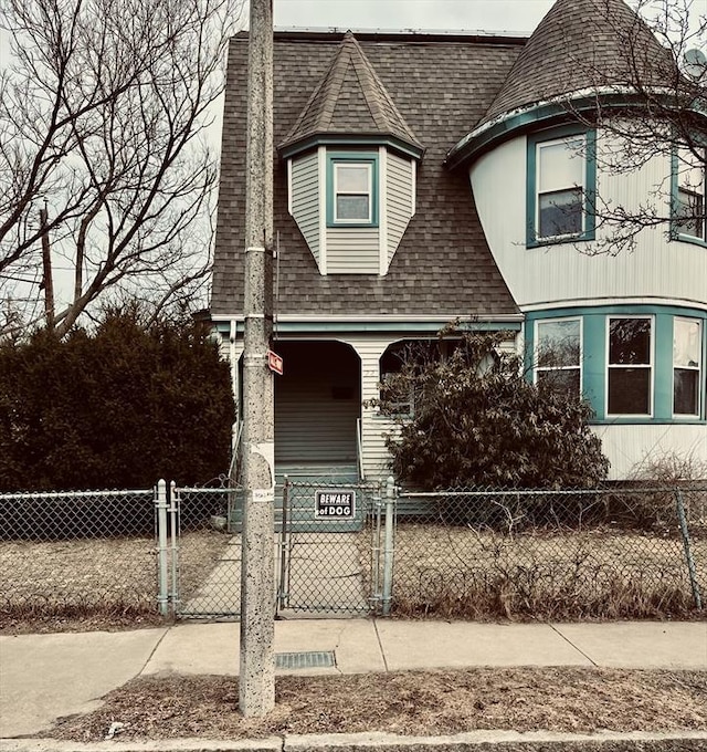 victorian house with a porch, a fenced front yard, a shingled roof, a gate, and a chimney