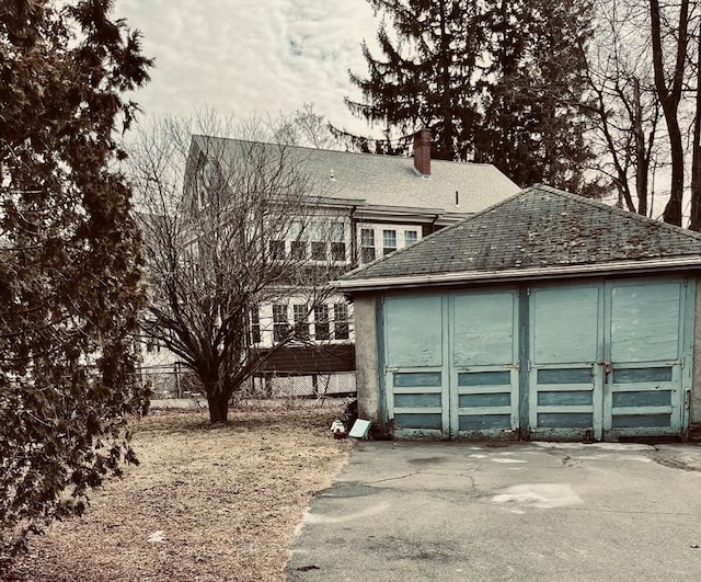 view of front of home featuring a chimney, an outdoor structure, and fence