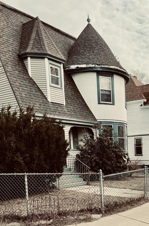 victorian house with roof with shingles and a fenced front yard