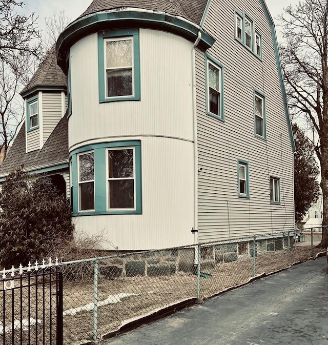 view of side of property with fence private yard and roof with shingles