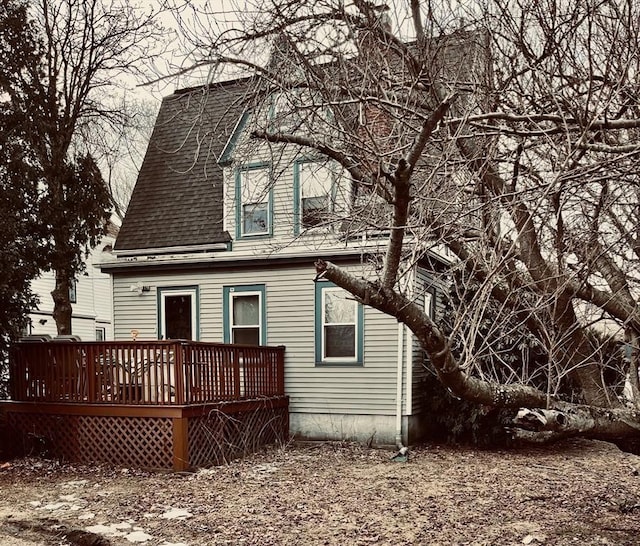 back of property with a deck and roof with shingles