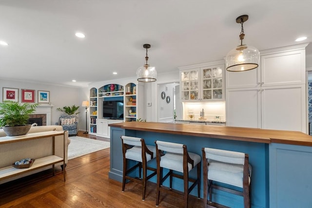 kitchen with dark wood-style floors, butcher block counters, white cabinets, and decorative light fixtures