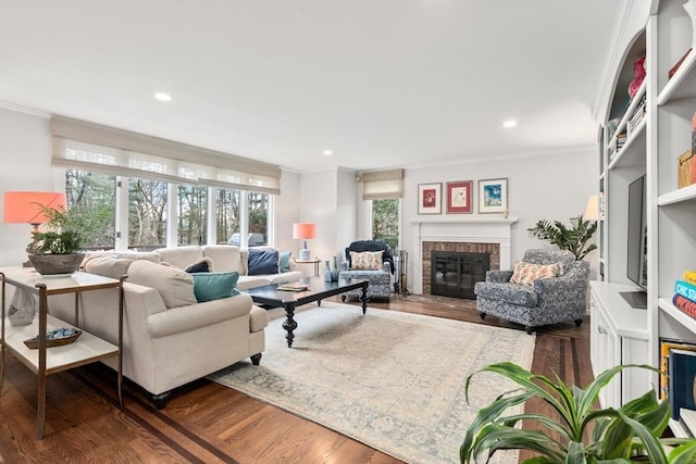 living area with a brick fireplace, wood finished floors, and crown molding