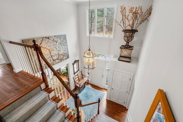 entrance foyer with stairway, a high ceiling, an inviting chandelier, wood finished floors, and baseboards