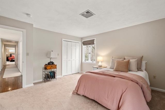 bedroom with a closet, carpet flooring, visible vents, and baseboards