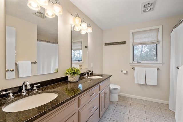 full bath featuring toilet, a sink, visible vents, and baseboards