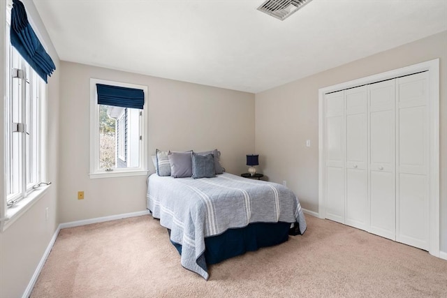 carpeted bedroom featuring a closet, visible vents, and baseboards