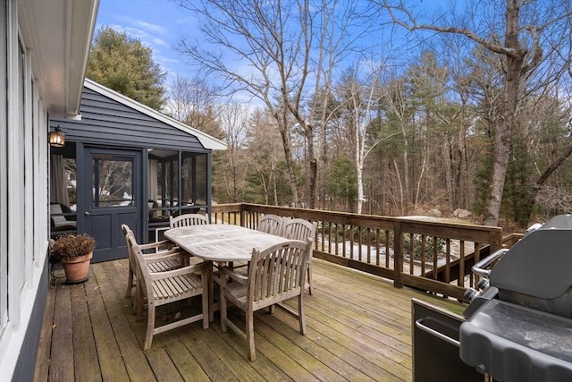 wooden deck with a sunroom, grilling area, and outdoor dining area