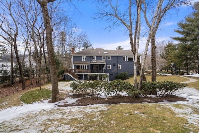 snow covered rear of property with stairs, a deck, and a chimney