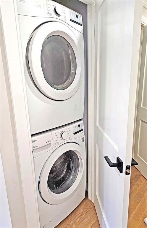 clothes washing area featuring light hardwood / wood-style flooring and stacked washer / drying machine