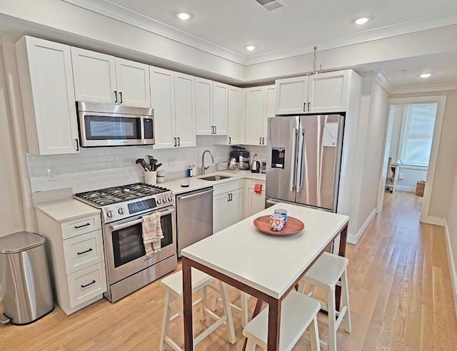 kitchen with appliances with stainless steel finishes, light hardwood / wood-style floors, and white cabinetry