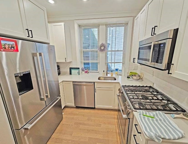 kitchen featuring light wood-type flooring, decorative backsplash, white cabinetry, sink, and high end appliances