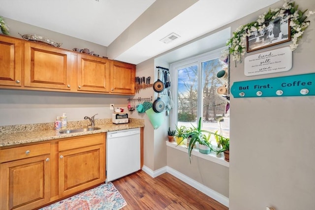 kitchen with hardwood / wood-style flooring, dishwasher, sink, and light stone countertops