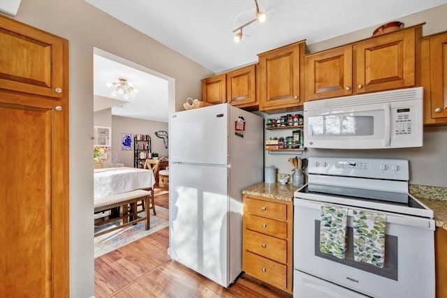 kitchen featuring light stone countertops, light wood-type flooring, and white appliances