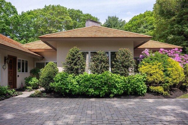 81 Countryside Ln, Milton, MA 02186 - view of property exterior with stucco siding and a chimney