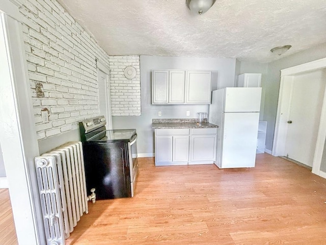 15 Circuit Ave E, Worcester, MA 01603 - kitchen featuring freestanding refrigerator, radiator, stainless steel electric range, brick wall, and light wood finished floors
