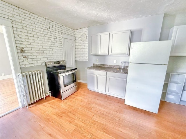 15 Circuit Ave E, Worcester, MA 01603 - kitchen featuring stainless steel electric range oven, radiator heating unit, freestanding refrigerator, brick wall, and light wood-type flooring