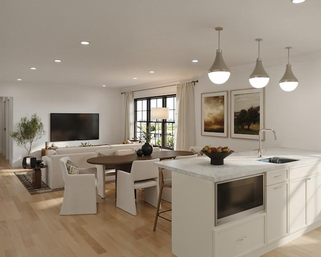 kitchen featuring a sink, built in microwave, light wood-style flooring, white cabinets, and recessed lighting