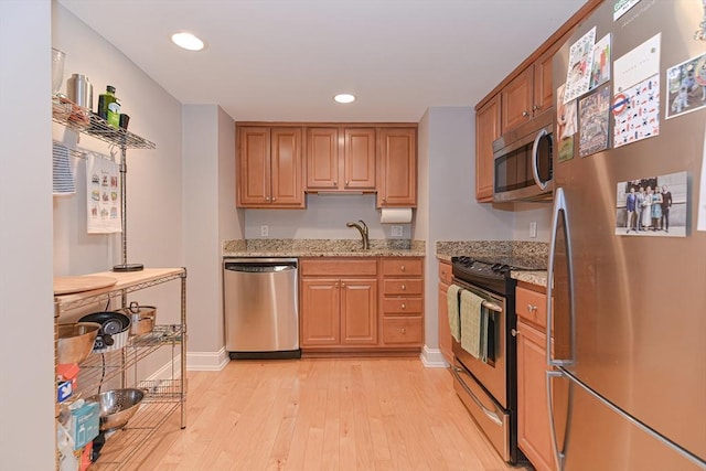 kitchen with light wood finished floors, baseboards, light stone counters, stainless steel appliances, and recessed lighting