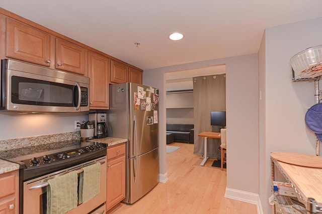 kitchen featuring appliances with stainless steel finishes, recessed lighting, light stone counters, and light wood-style floors