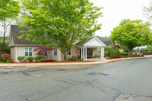 view of front facade featuring stone siding, a porch, and a shingled roof
