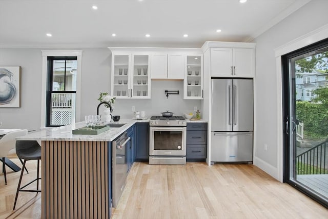 61 Lyndhurst St Unit A, Boston, MA 02124 - kitchen with appliances with stainless steel finishes, light wood-style flooring, white cabinetry, light stone counters, and crown molding