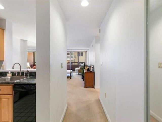 hall with light colored carpet and sink