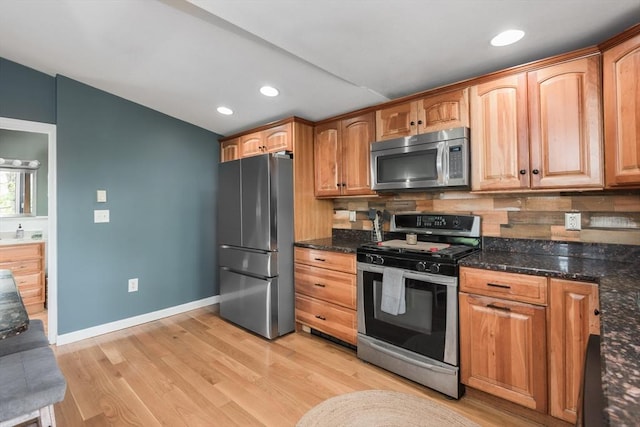 38 Colonial Rd, Weymouth, MA 02191 - kitchen with appliances with stainless steel finishes, decorative backsplash, baseboards, light wood-style floors, and dark stone countertops