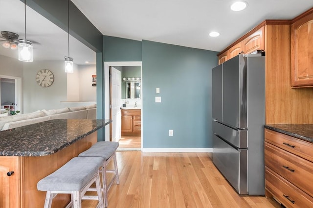 38 Colonial Rd, Weymouth, MA 02191 - kitchen with freestanding refrigerator, a breakfast bar area, light wood finished floors, recessed lighting, and dark stone countertops