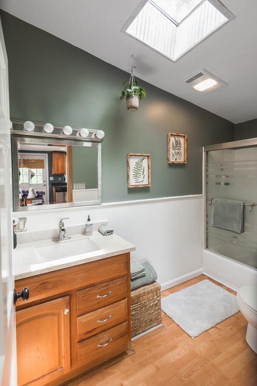 38 Colonial Rd, Weymouth, MA 02191 - full bathroom featuring lofted ceiling, a skylight, vanity, wood finished floors, and a wainscoted wall