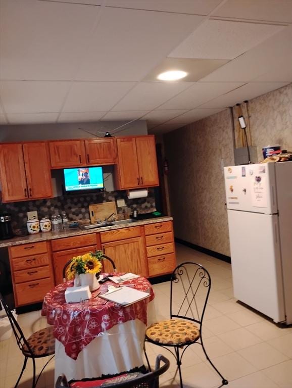 kitchen featuring white refrigerator, sink, a paneled ceiling, and decorative backsplash