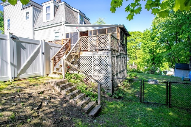 view of home's exterior with a gate, stairs, a sunroom, a shingled roof, and mansard roof