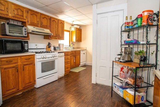 kitchen with white appliances, under cabinet range hood, light countertops, brown cabinets, and a paneled ceiling