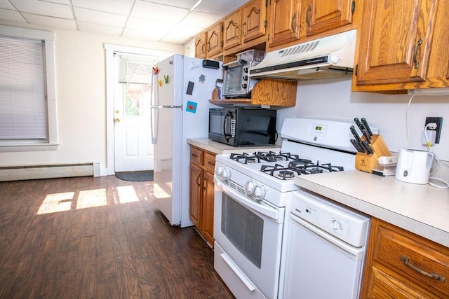 kitchen with white appliances, under cabinet range hood, light countertops, dark wood finished floors, and a paneled ceiling