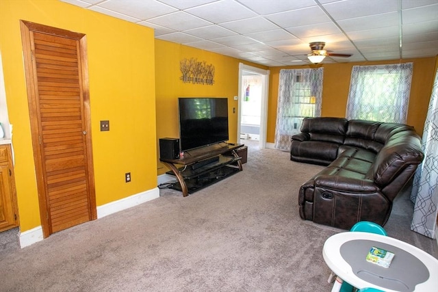 living area with carpet flooring, ceiling fan, baseboards, and a paneled ceiling