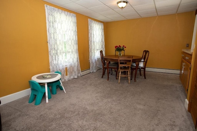 dining space with a baseboard heating unit, a paneled ceiling, carpet floors, and baseboards