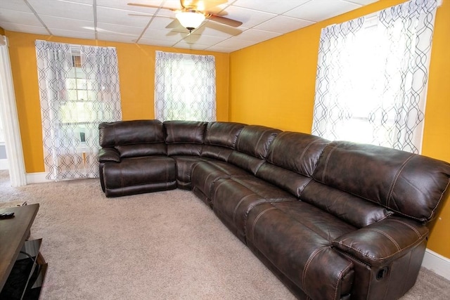 living room with ceiling fan, a drop ceiling, carpet flooring, and baseboards