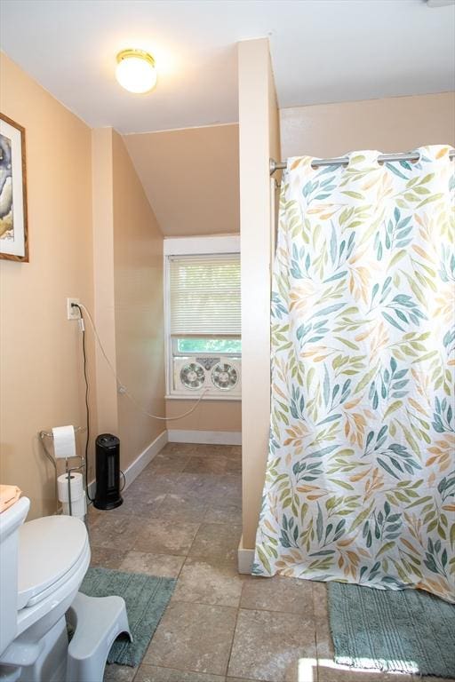 full bath featuring baseboards, toilet, curtained shower, and stone finish floors