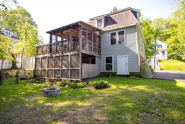 rear view of property featuring an outdoor fire pit, a gate, a sunroom, a chimney, and mansard roof