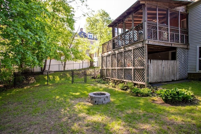 view of yard featuring an outdoor fire pit, a sunroom, and a gate