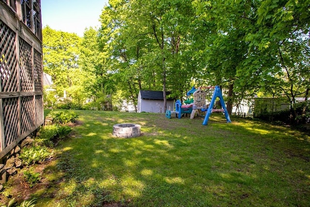 view of green lawn with a fire pit, a shed, and an outdoor structure