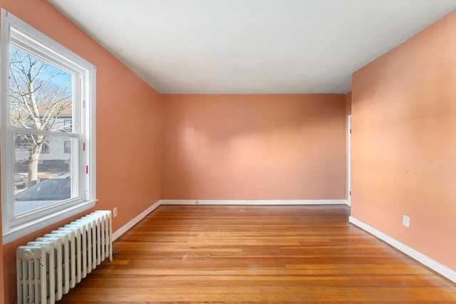 empty room featuring radiator heating unit and light hardwood / wood-style flooring