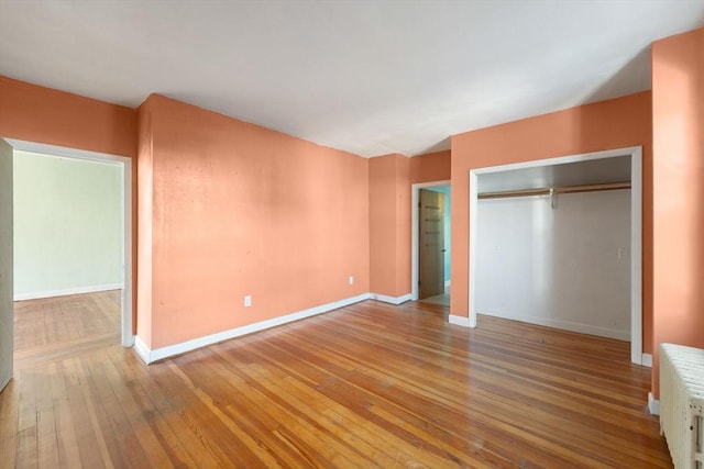 unfurnished bedroom with radiator heating unit, light hardwood / wood-style flooring, and a closet