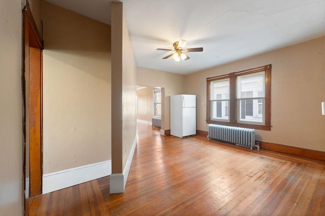 unfurnished room with ceiling fan, light wood-type flooring, and radiator heating unit