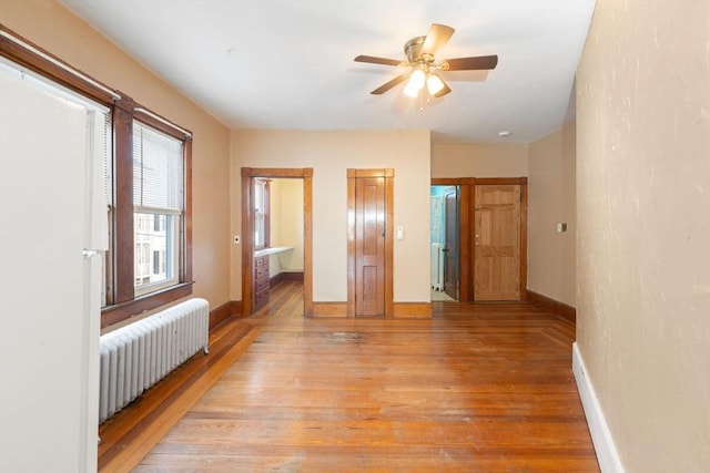 empty room with radiator heating unit, light hardwood / wood-style floors, and ceiling fan