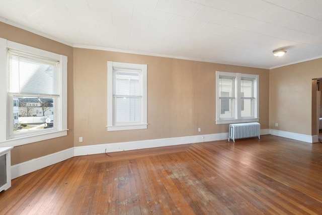 spare room with a healthy amount of sunlight, wood-type flooring, radiator heating unit, and crown molding